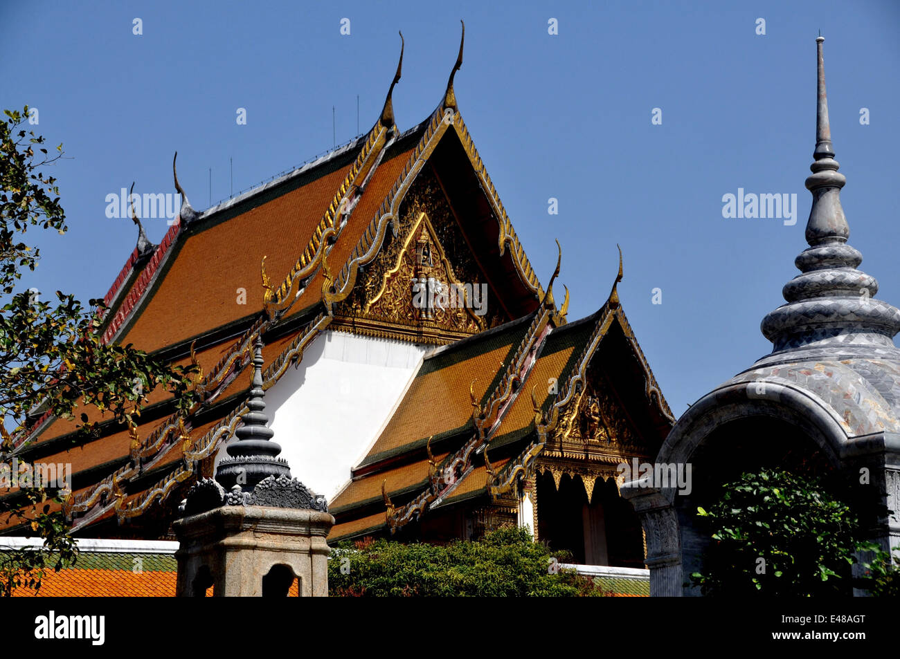 Bangkok, Thailand: Ubosot sanctuary hall with its gabled roofs, ornate tympanums, and chofah ornaments at Wat Suthat Stock Photo