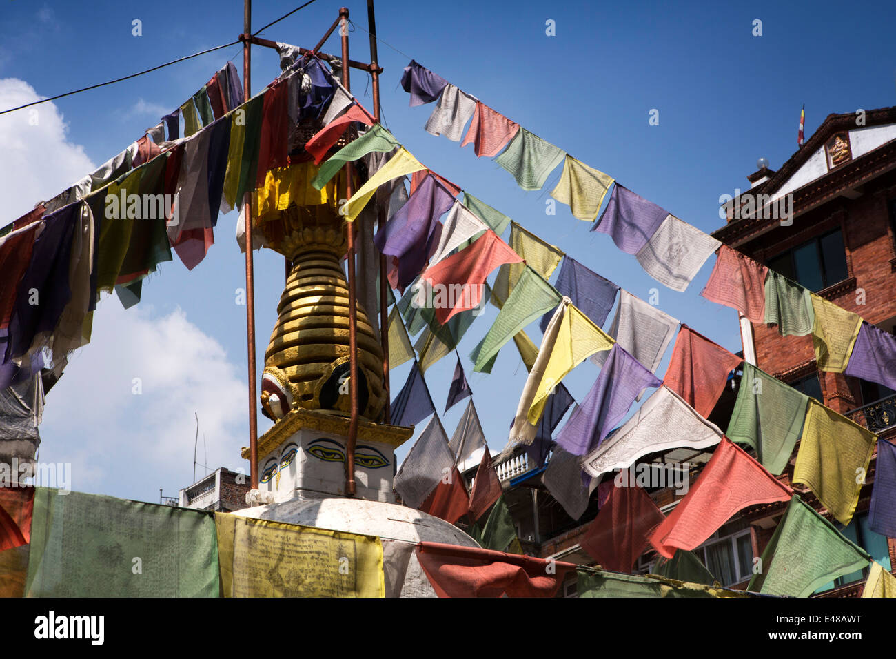 Nepal, Kathmandu, Thamel Marg, small local Buddhist stupa with all seeing eye and colourful prayer flags Stock Photo