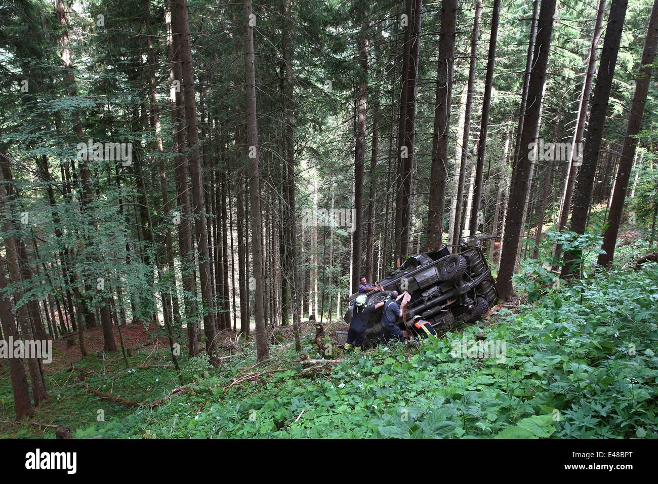 People work to free an SUV in the mountains near Oberstdorf, Germany, 05 July 2014. Several people were in the car when is went off the road and crashed down a cliff. One person was killed in the accident. Photo: KARL-JOSEF HILDENBRAND/dpa Stock Photo