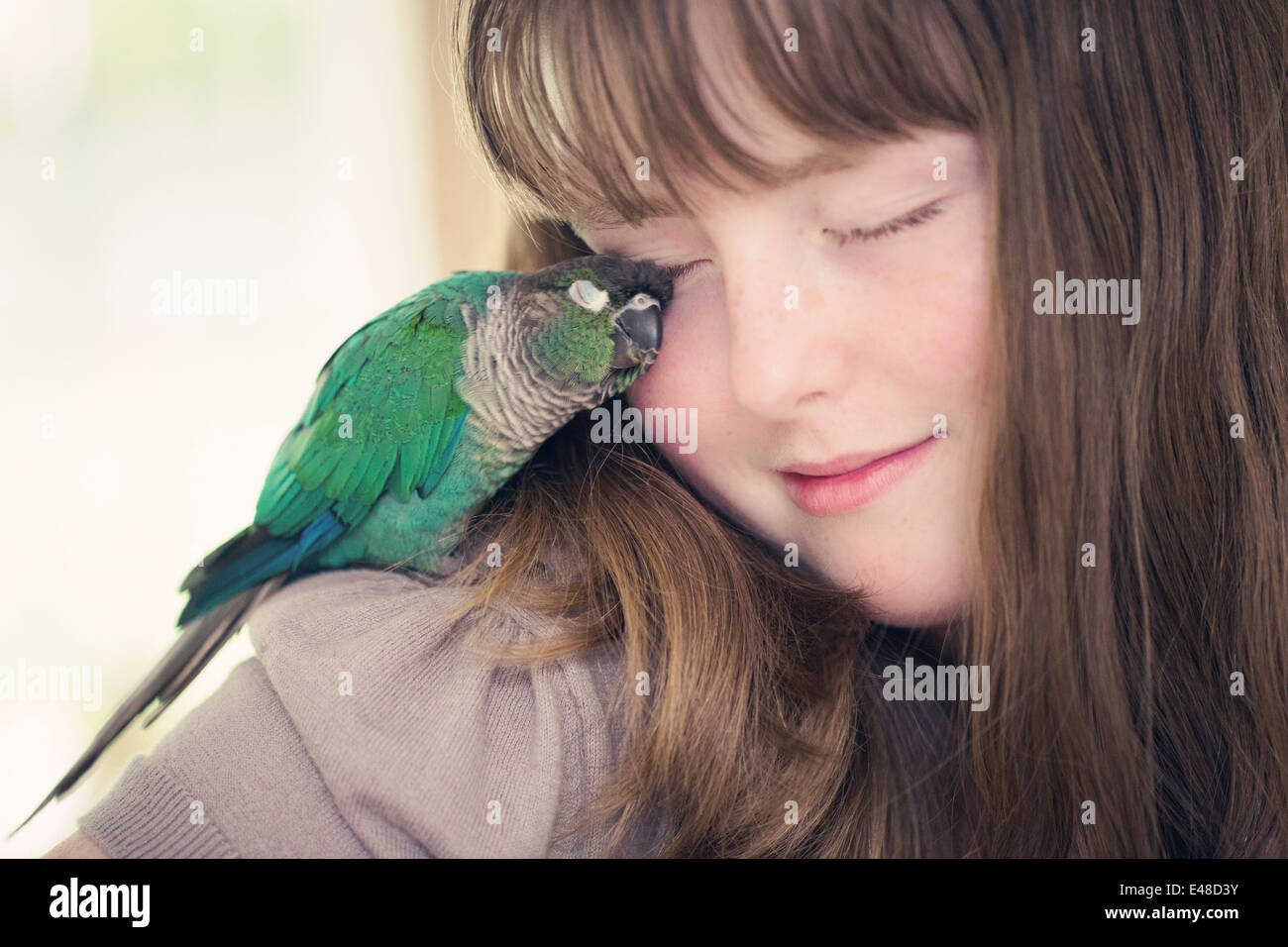 Portrait of girl (13-15) cuddling with parrot Stock Photo