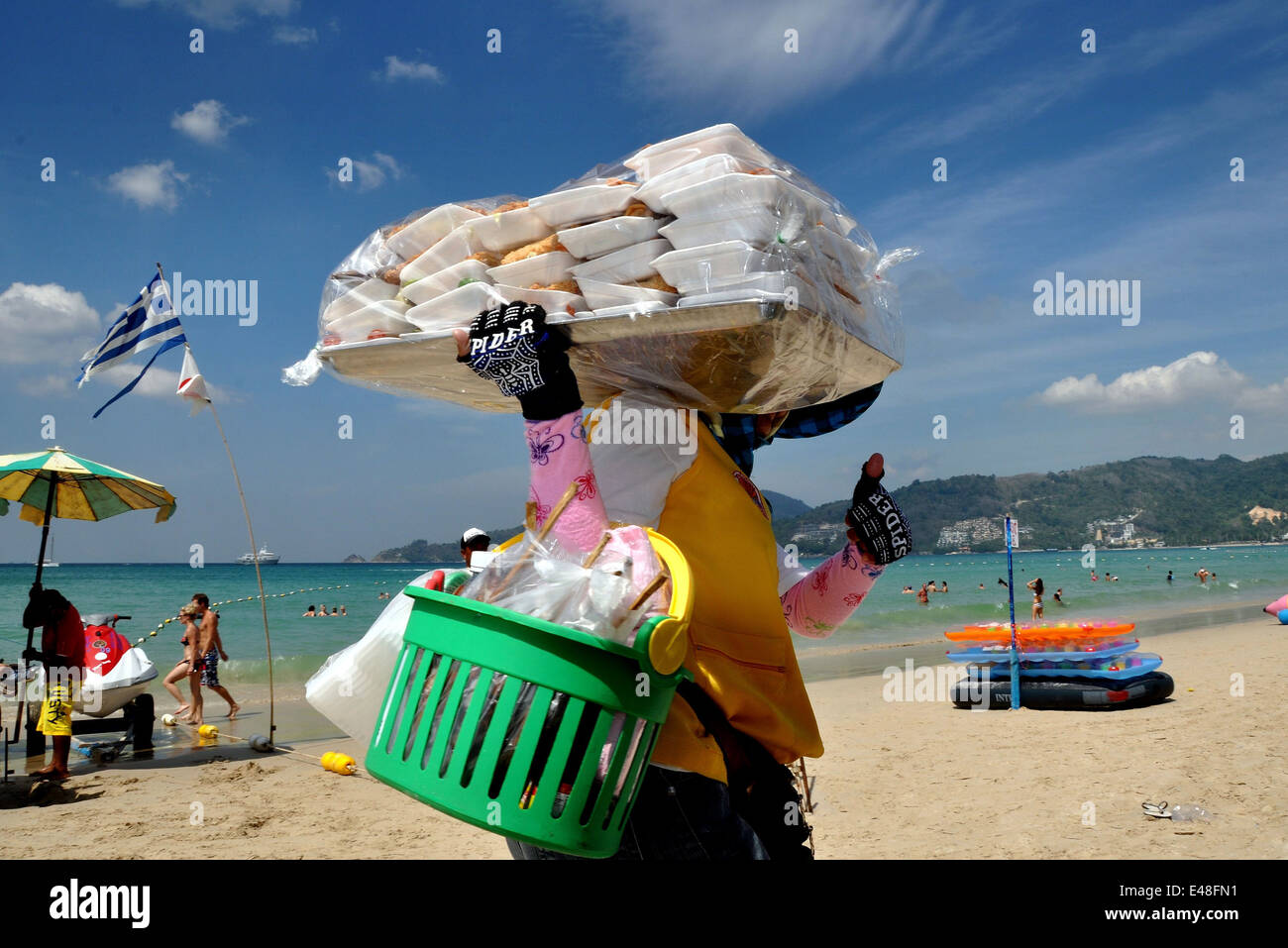 Patong City, Phuket, Thaland : Woman food vendor carrying her wares walks along Patong Beach Stock Photo