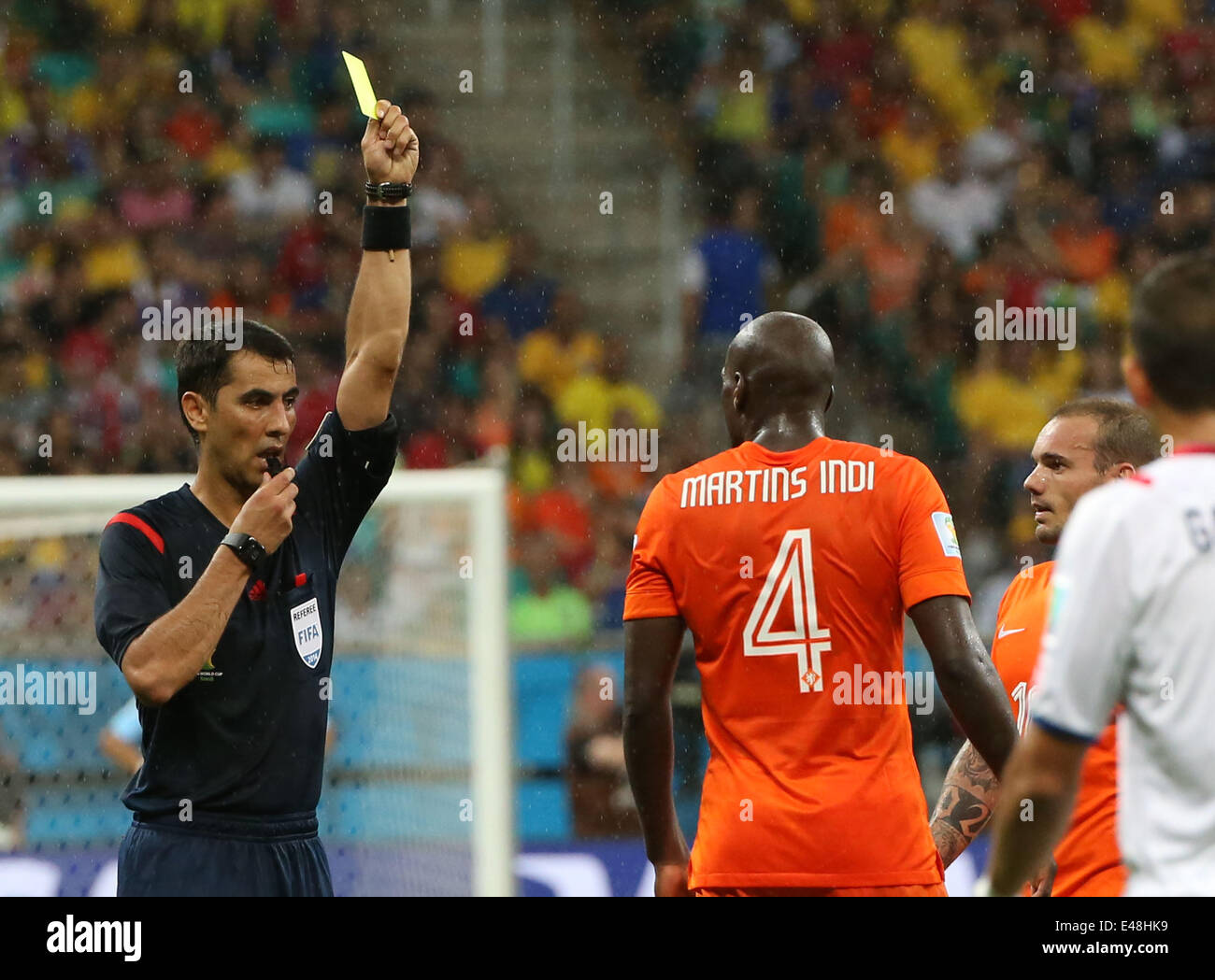 Salvador, Brazil. 5th July, 2014. Uzbekistan's referee Ravshan Irmatov (1st L) shows a yellow card to Netherlands' Bruno Martins Indi (2nd L) during a quarter-finals match between Netherlands and Costa Rica of 2014 FIFA World Cup at the Arena Fonte Nova Stadium in Salvador, Brazil, on July 5, 2014. Credit:  Cao Can/Xinhua/Alamy Live News Stock Photo