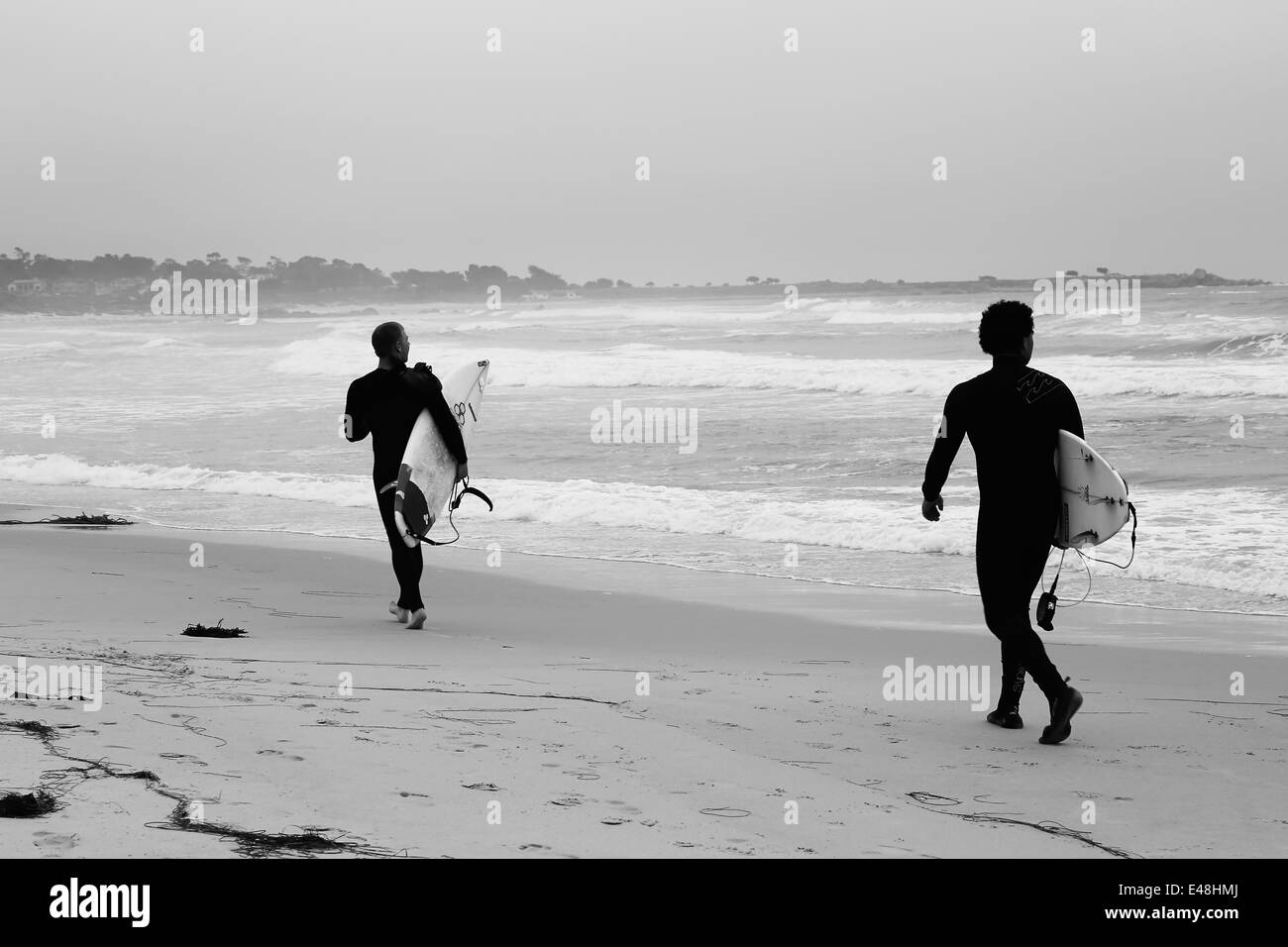 Surfers holding surfboards getting ready to go dive into the surf, on