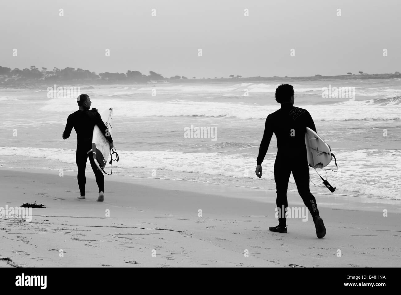 Surfers holding surfboards getting ready to go dive into the surf, on
