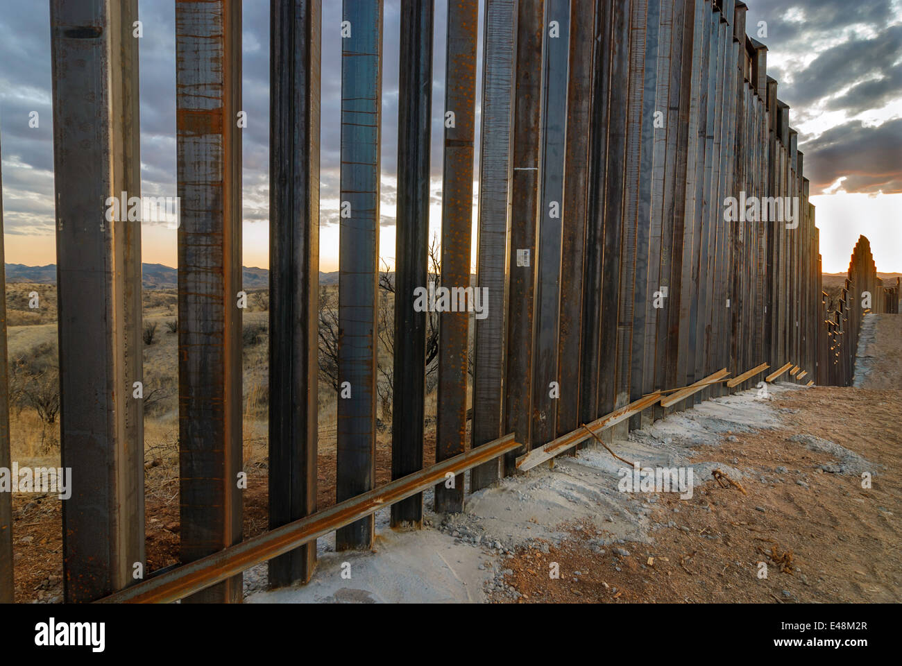 Sunset at US Border Fence, east of Nogales Arizona USA, viewed from US side, looking west toward Nogales, Arizona Stock Photo