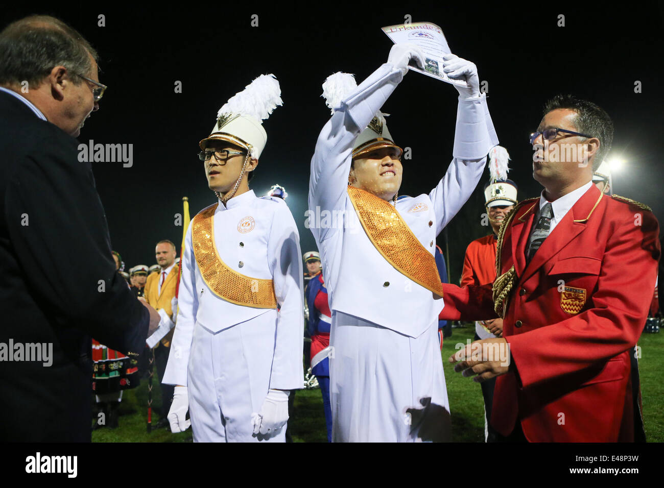 Rastede, Germany. 5th July, 2014. Guo Yuanchi (2nd R), conductor of Beihang University's marching band, shows the certificate of wining the highest score of a marching band's competition during the 59th International Rasteder Music Day in Rastede, Germany, on July 5, 2014. More than 50 bands and thousands of musicians from 6 countries and regions took part in the three-day International Rasteder Music Day, one of the oldest music festivals in Germany. Credit:  Zhang Fan/Xinhua/Alamy Live News Stock Photo