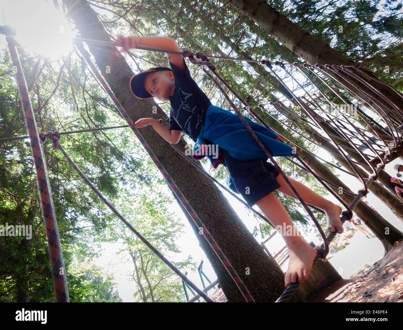 Boy balancing barefoot on rope in rope jungle gym Stock Photo Alamy