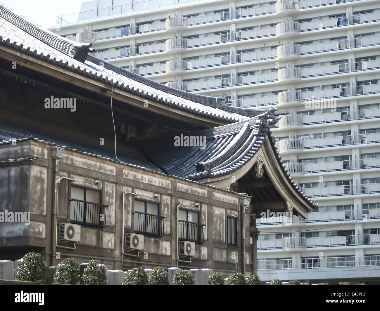 An old Japanese building with traditional pagoda roof in front of a modern apartment block in Tokyo city, Japan. Stock Photo