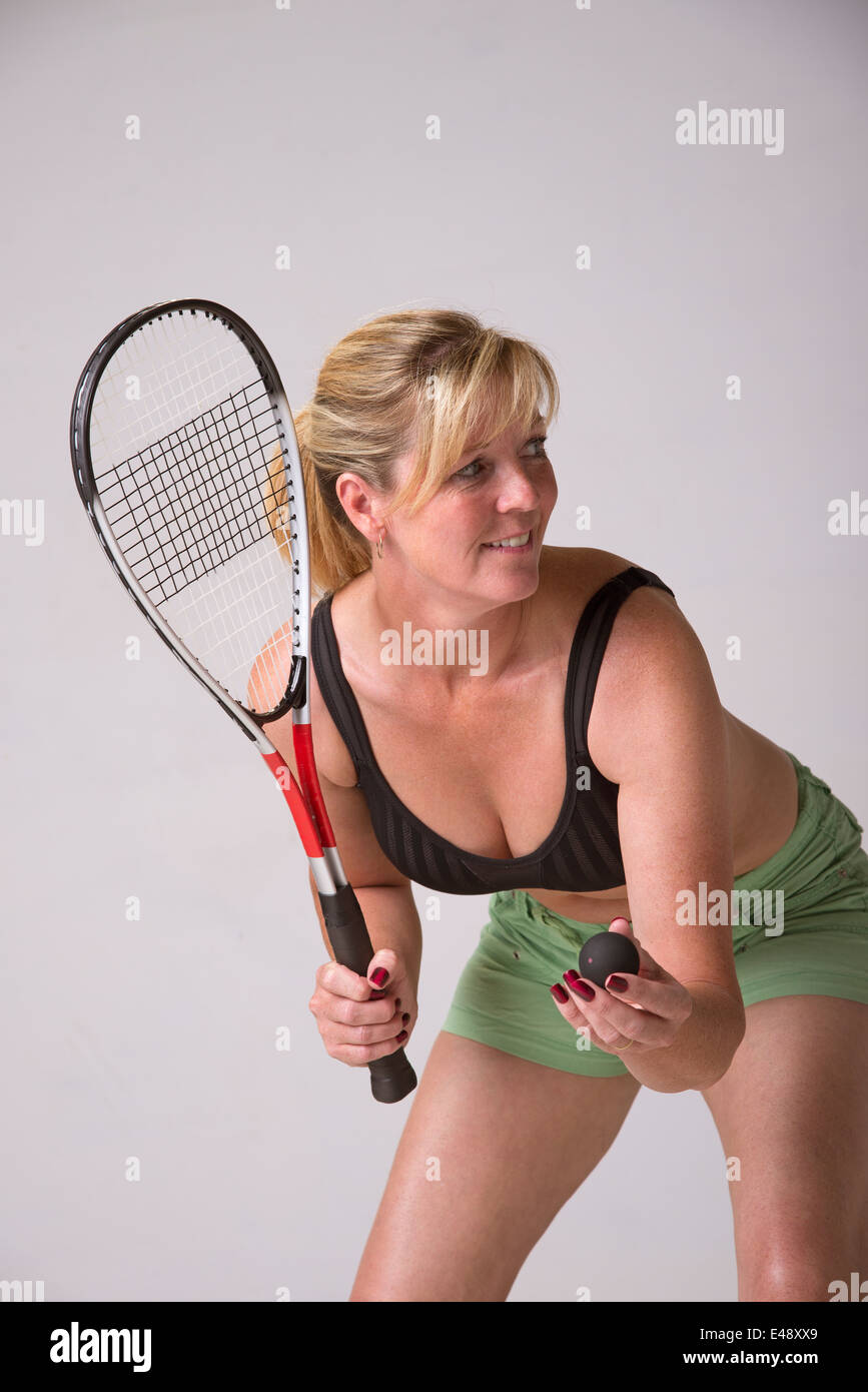 Woman in sports bra and green shorts playing squash Stock Photo