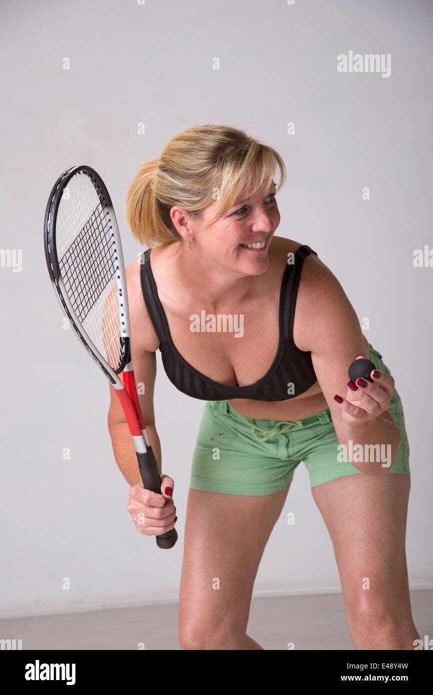 Woman in sports bra and green shorts playing squash Stock Photo
