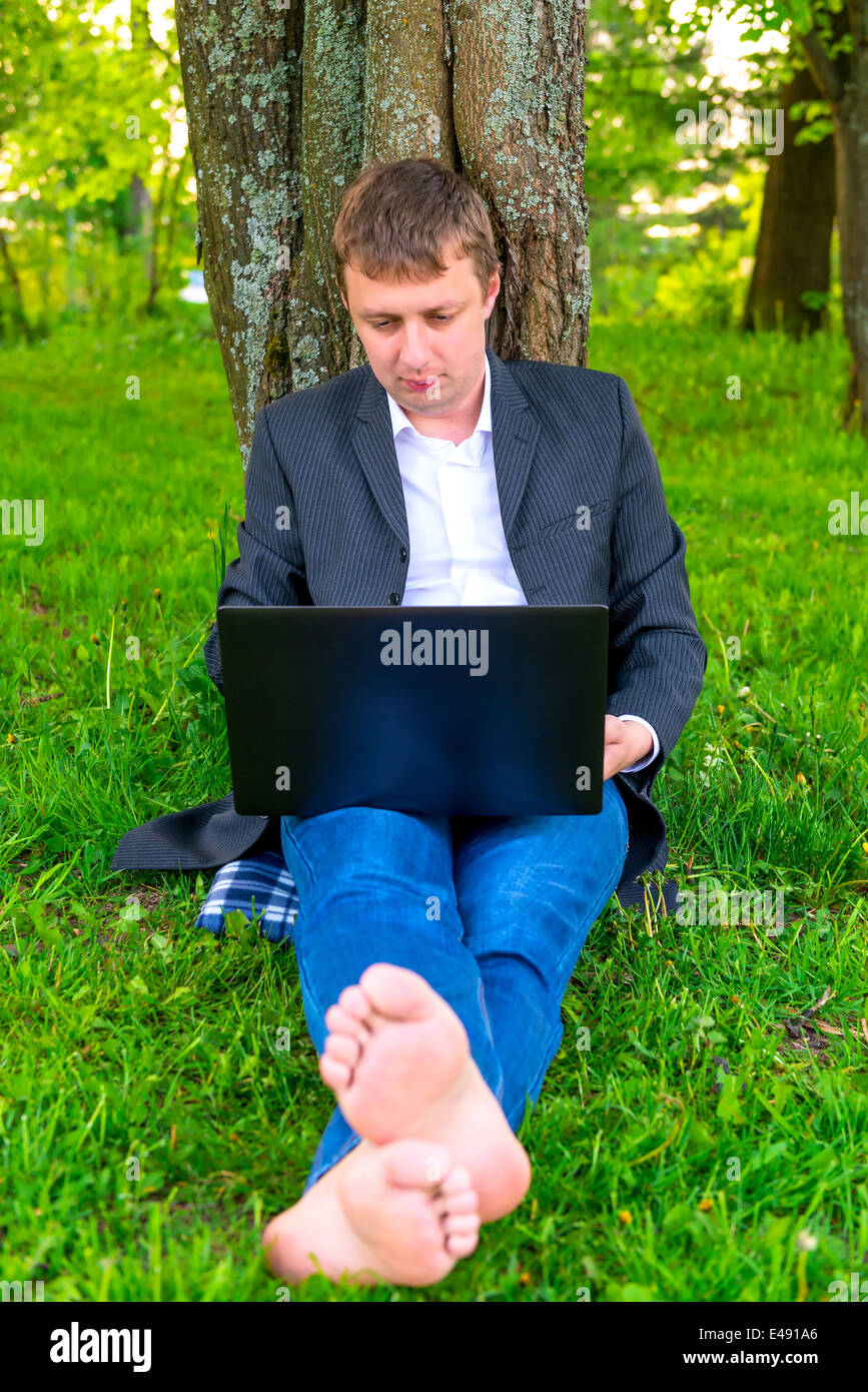 Barefoot businessman with a computer in the park Stock Photo