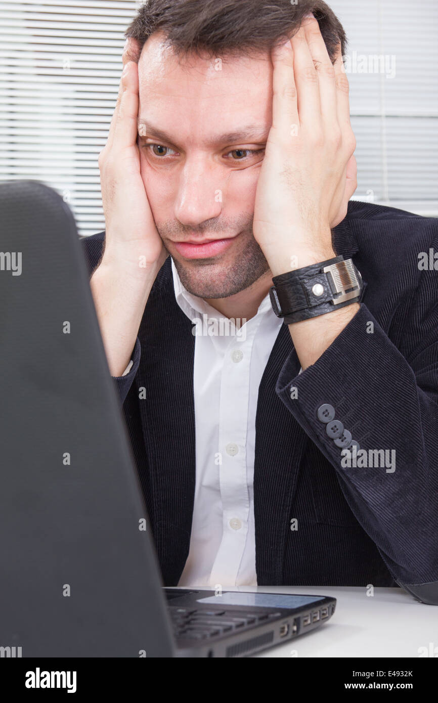 adult business man looking at screen laptop computer with a shocked upset expression, tired