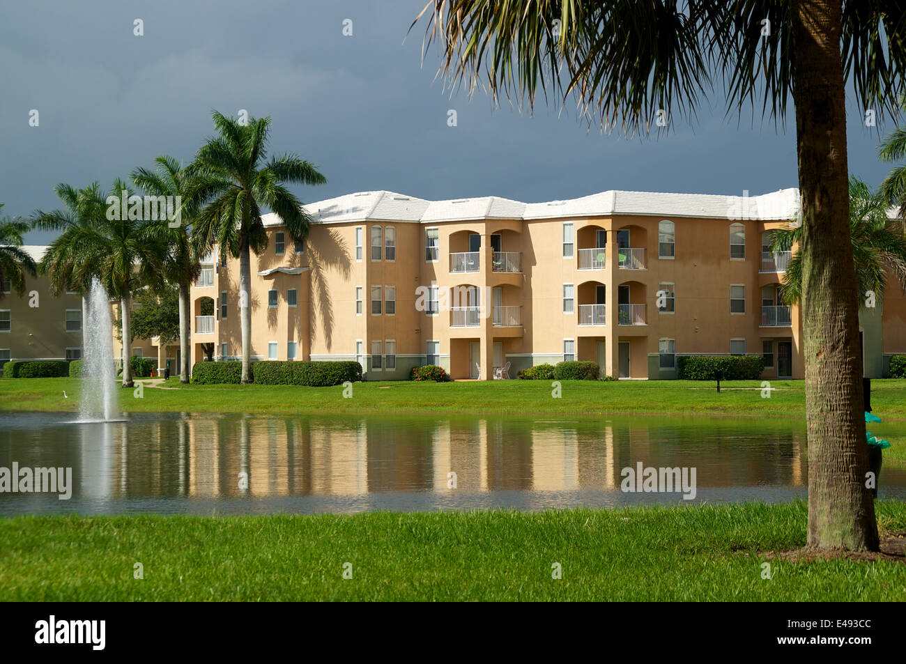 Looking across a pond towards a three story apartment complex in Naples, Florida, with a stormy