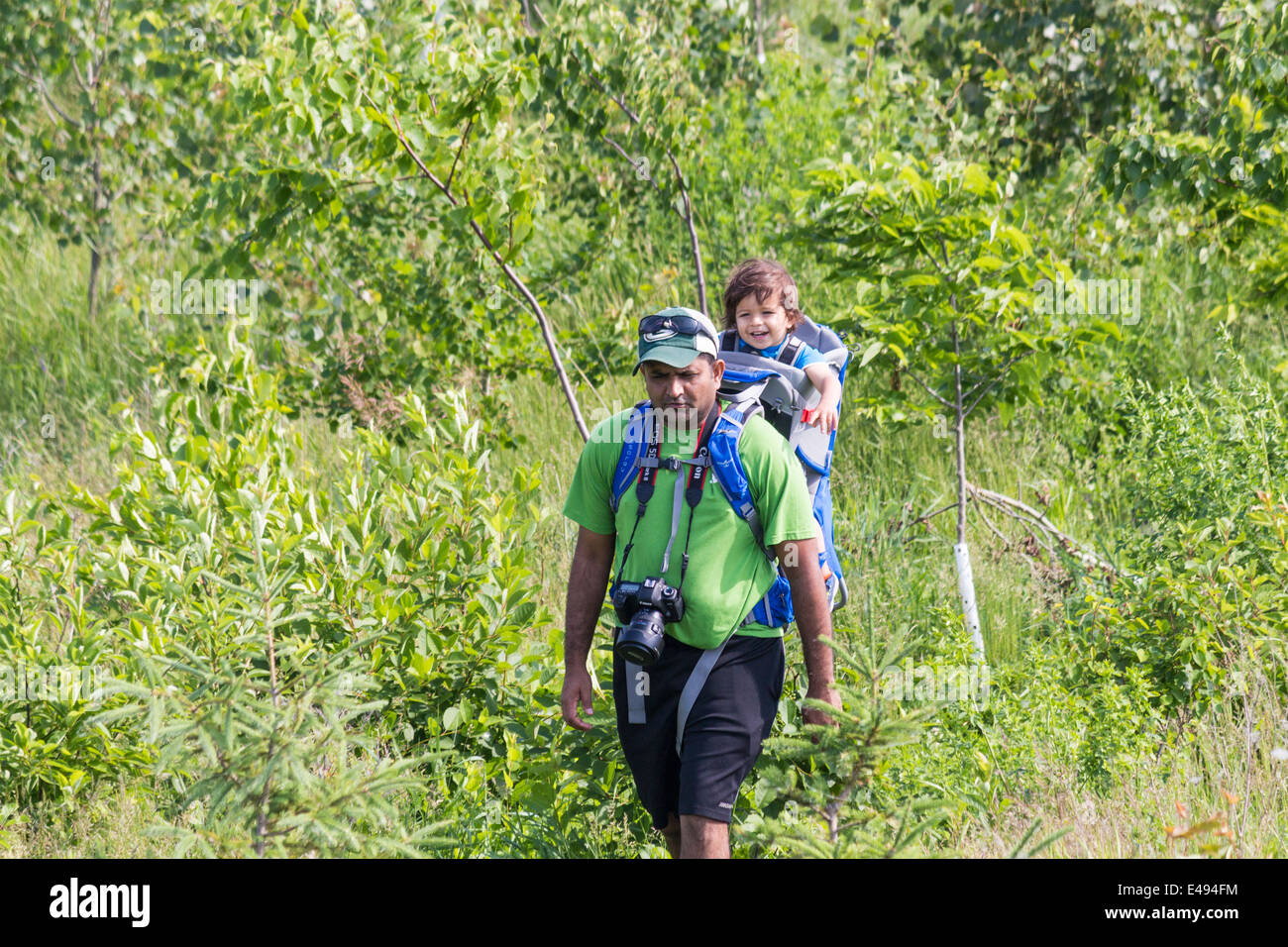 Man with child in backpack hiking through the Leslie St spit or Tommy Tompson Park in downtown Toronto Ontario Stock Photo