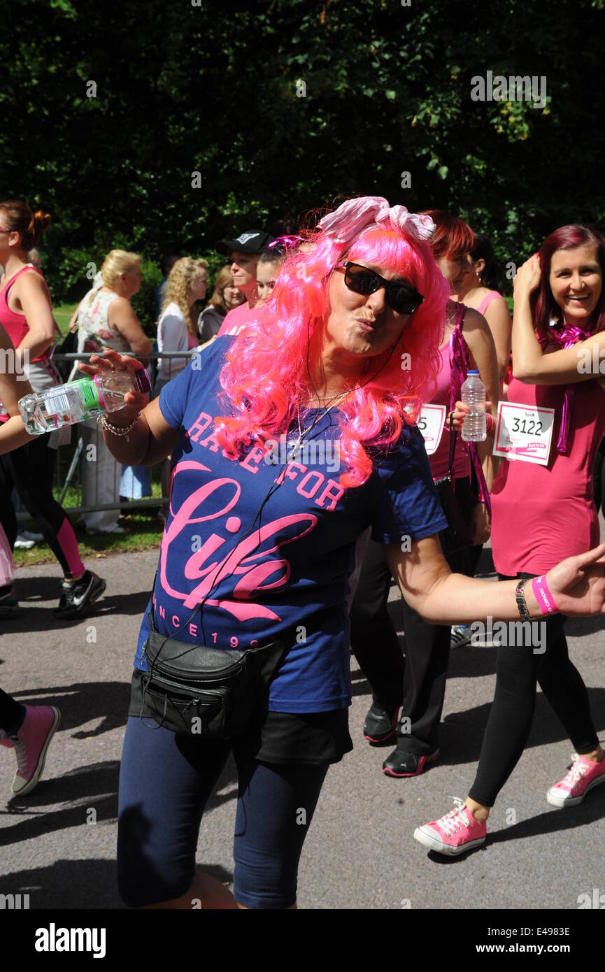 Liverpool, UK. Sunday 6th July 2014. Woman in a long pink wig blows a kiss. Cancer Research UK’s Race for Life is a series of 5k or 10k women-only fundraising events, which are raising money for research to help beat all 200 types of cancer sooner. This event was the Liverpool race around Sefton Park. Credit:  David Colbran/Alamy Live News Stock Photo