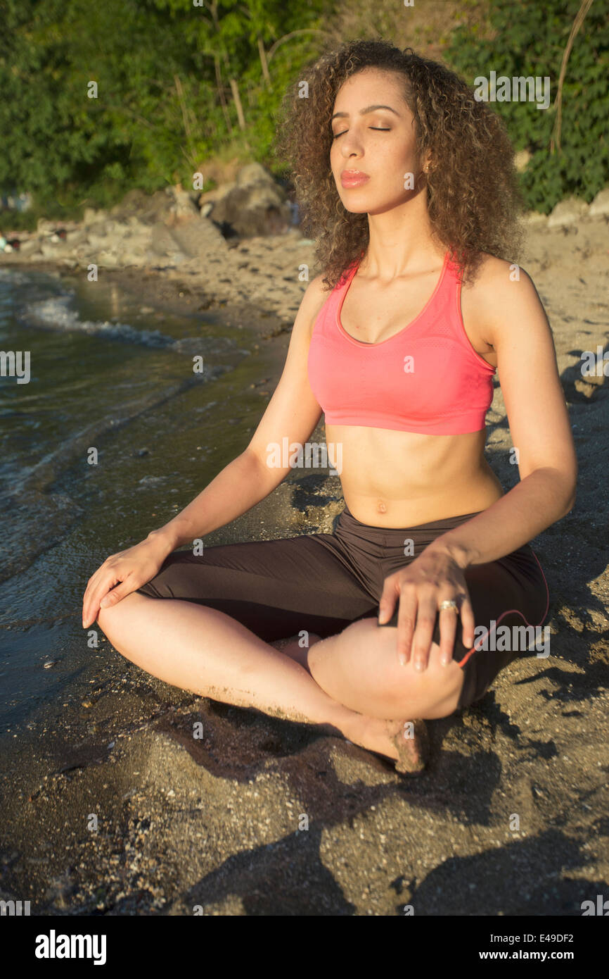 Young woman meditating on the beach. Stock Photo