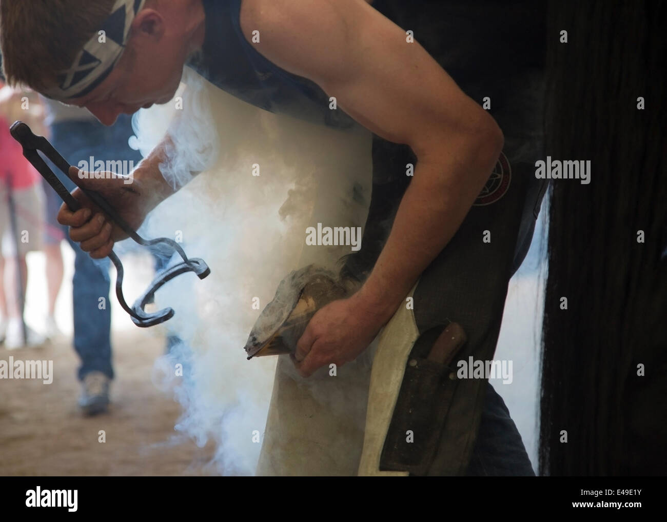 Calgary, Alberta, Canada. 06th July, 2014. Farrier fitting hot horse shoe to the horse's hoof as he competes in the last moments of the final round of the World Championships Blacksmiths' competition at the Calgary Stampede on Sunday, July 6, 2014. The top five farriers are competing for the title of world champion in this longstanding tradition at the Stampede. Calgary, Alberta, Canada. Credit:  Rosanne Tackaberry/Alamy Live News Stock Photo