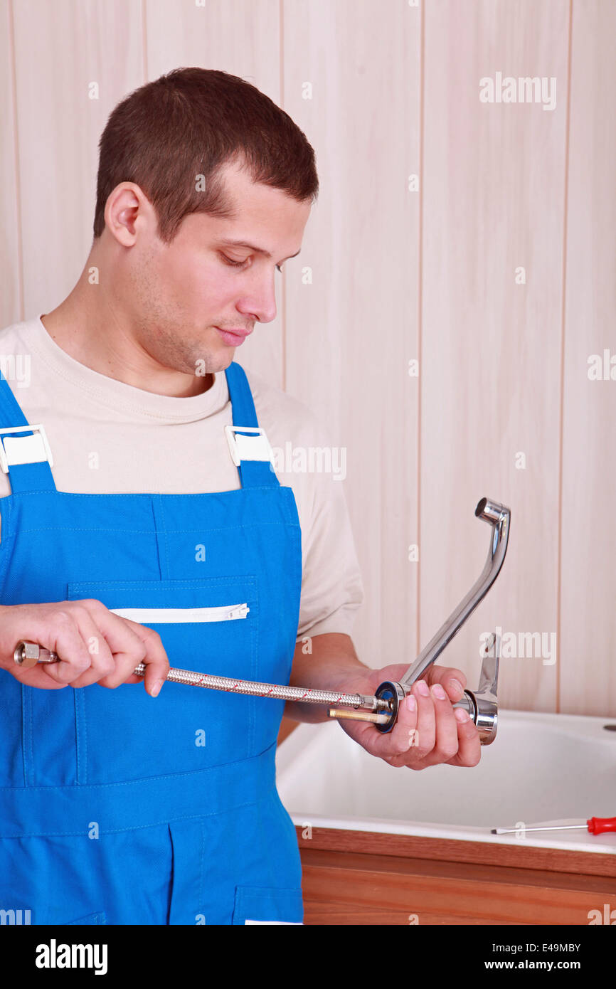 Plumber fitting a tap on a kitchen sink Stock Photo