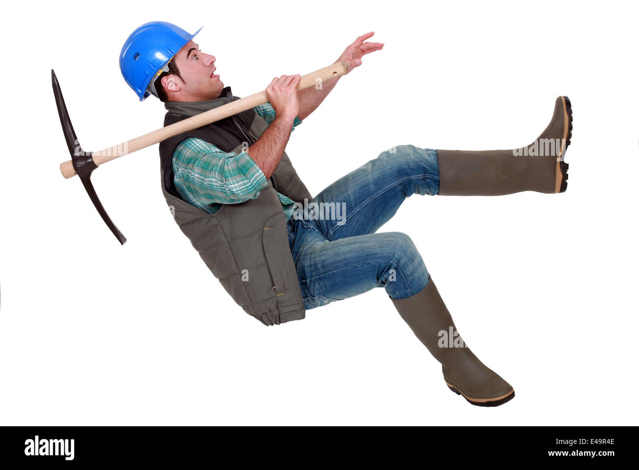 Man with pick-axe falling off chair Stock Photo