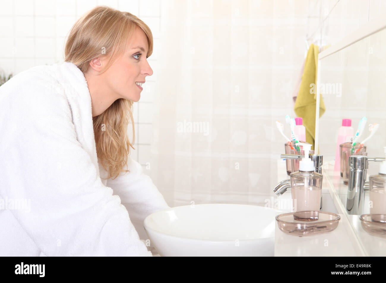 Woman looking into bathroom mirror Stock Photo - Alamy