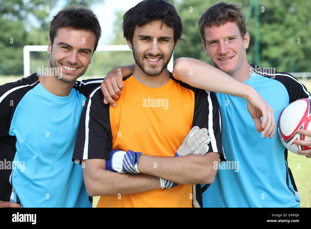 Three smiling footballers with ball Stock Photo