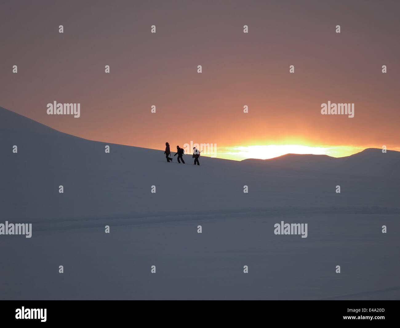 Trekking in winter snow as the sun rises over the mountains after the four month winter dark period, Svalbard, Arctic, Norway Stock Photo