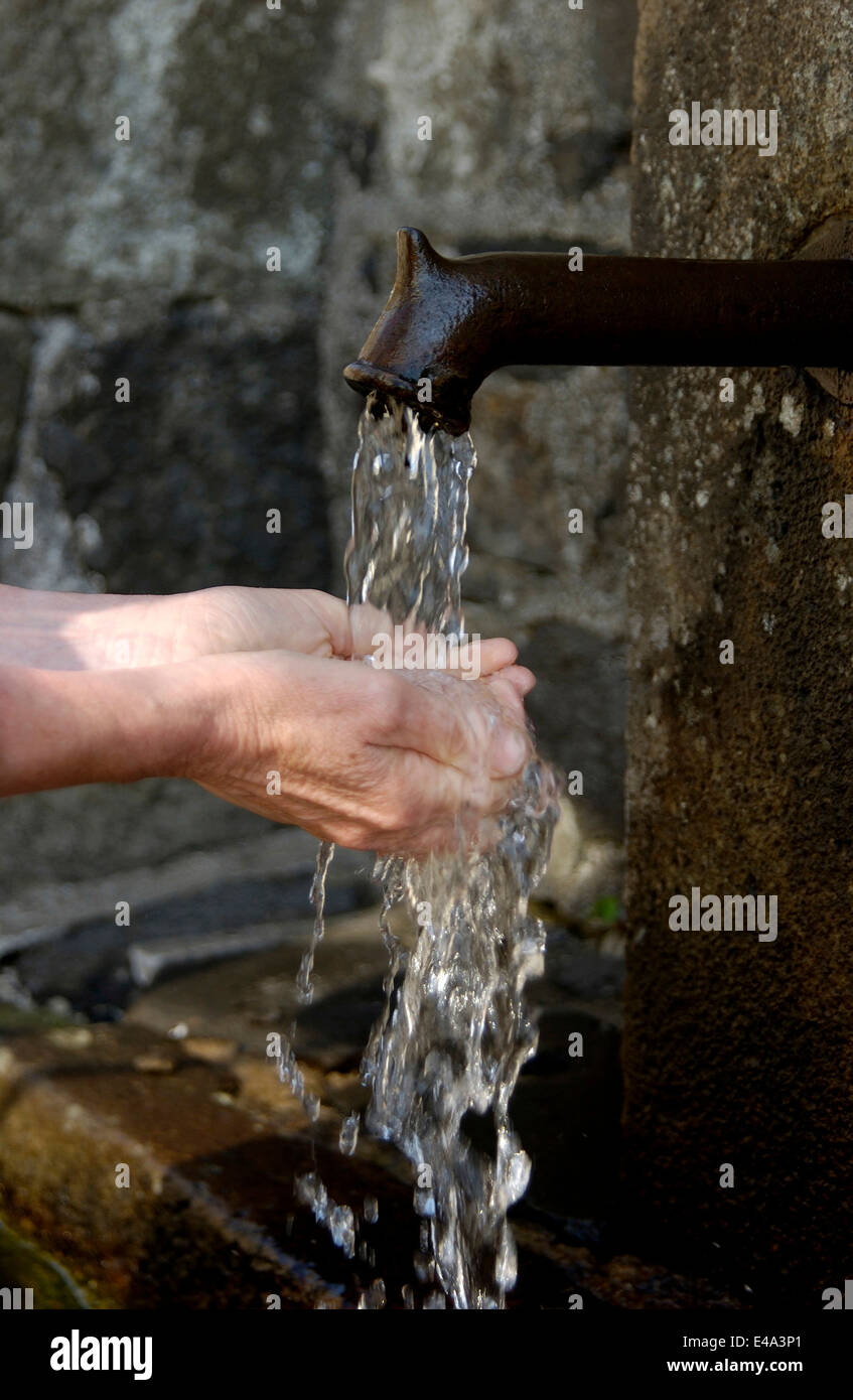 Washing hands at an outdoor spring water tap Stock Photo
