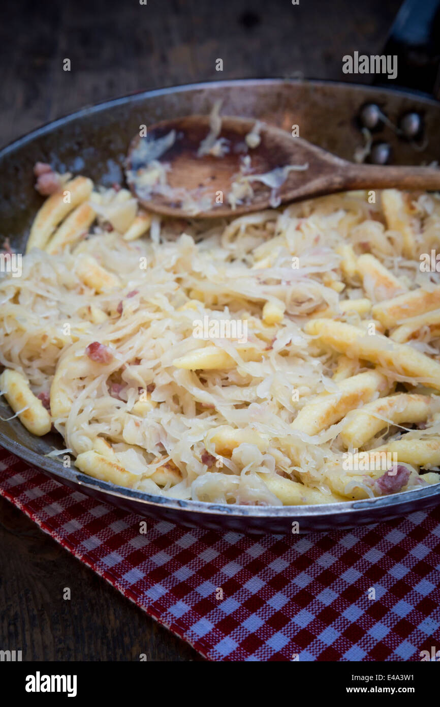 Frying pan of fingershaped potato dumplings with sauerkraut and bacon