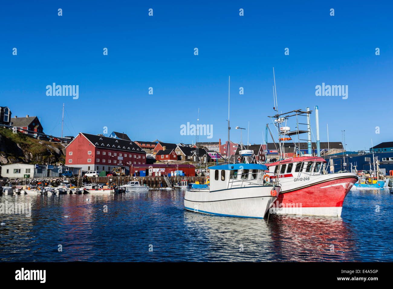 Commercial fishing and whaling boats line the busy inner harbor in the town of Ilulissat, Greenland, Polar Regions Stock Photo