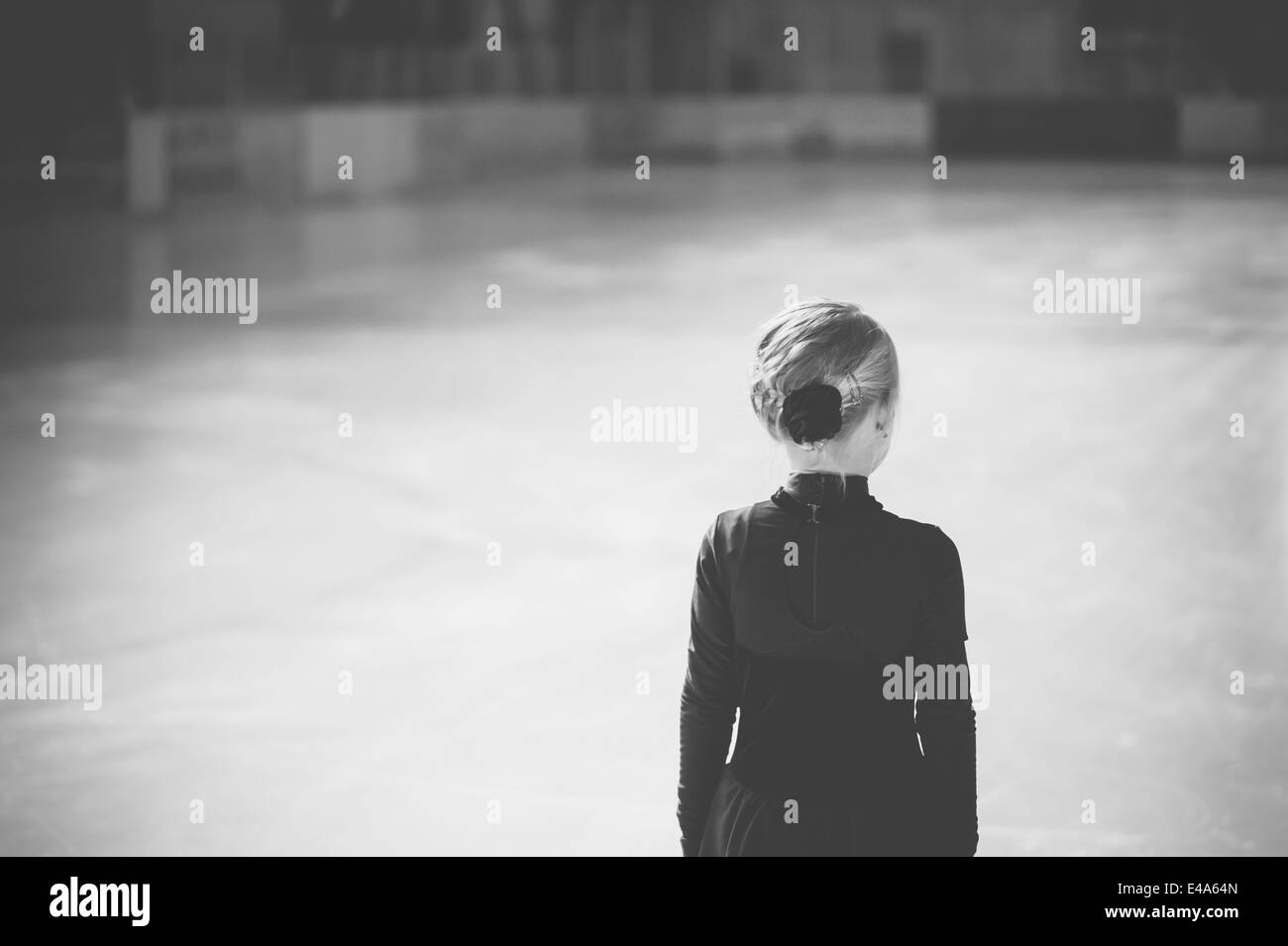 Young female figure skater standing on ice rink at competition, back view Stock Photo