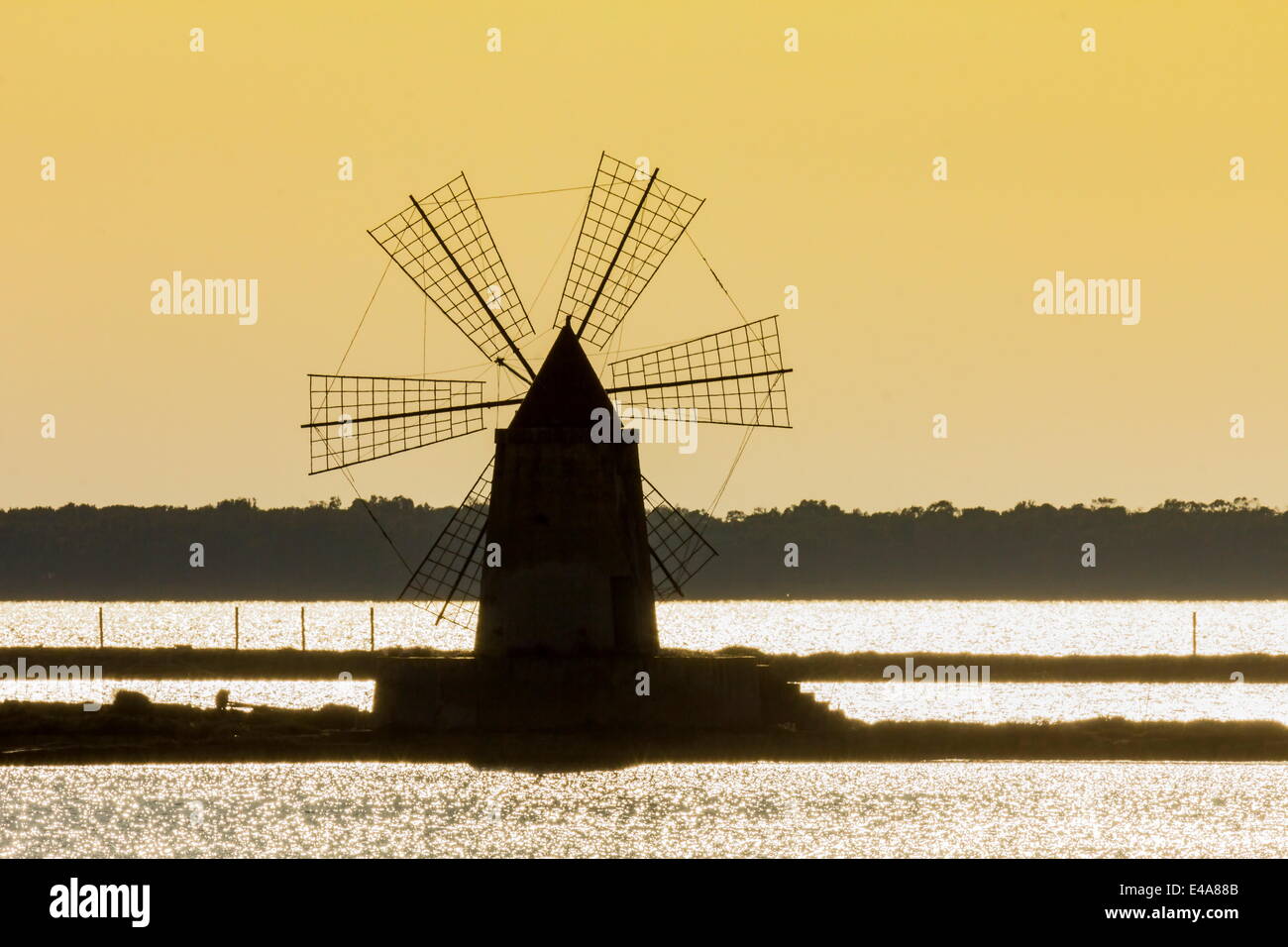 Silhouette of old windmill used to raise water from the Stagnone Lagoon into salt pans south of Trapani, Marsala, Sicily, Italy Stock Photo