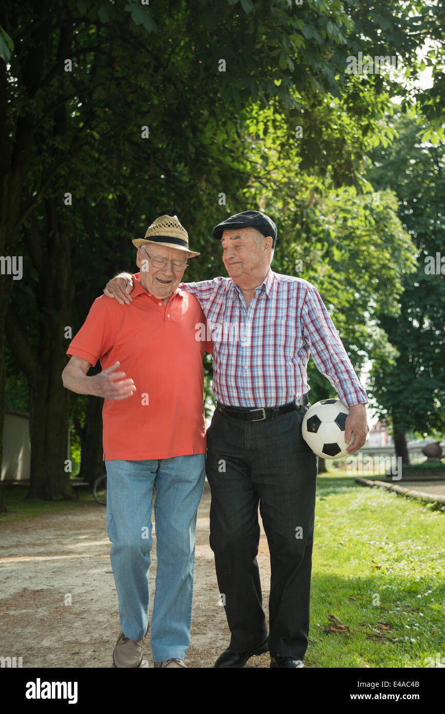 Two old friends walking in the park with football Stock Photo