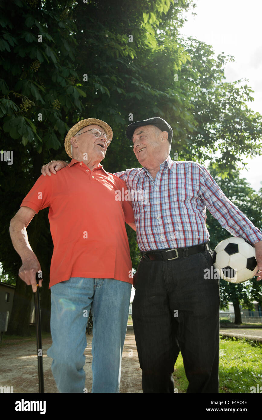 Two old friends walking in the park with football Stock Photo