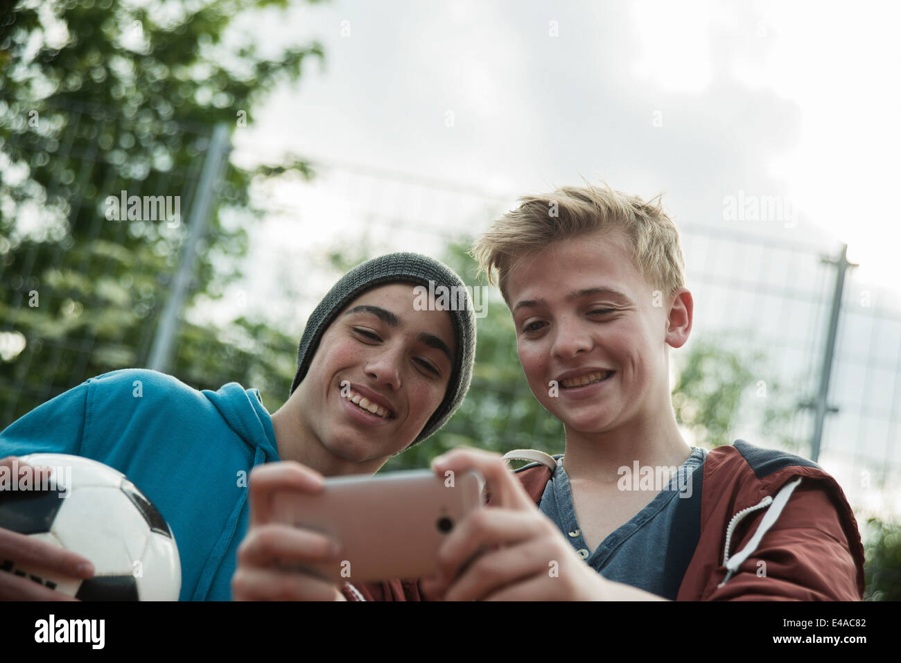 Two friends with soccer ball looking at cell phone Stock Photo