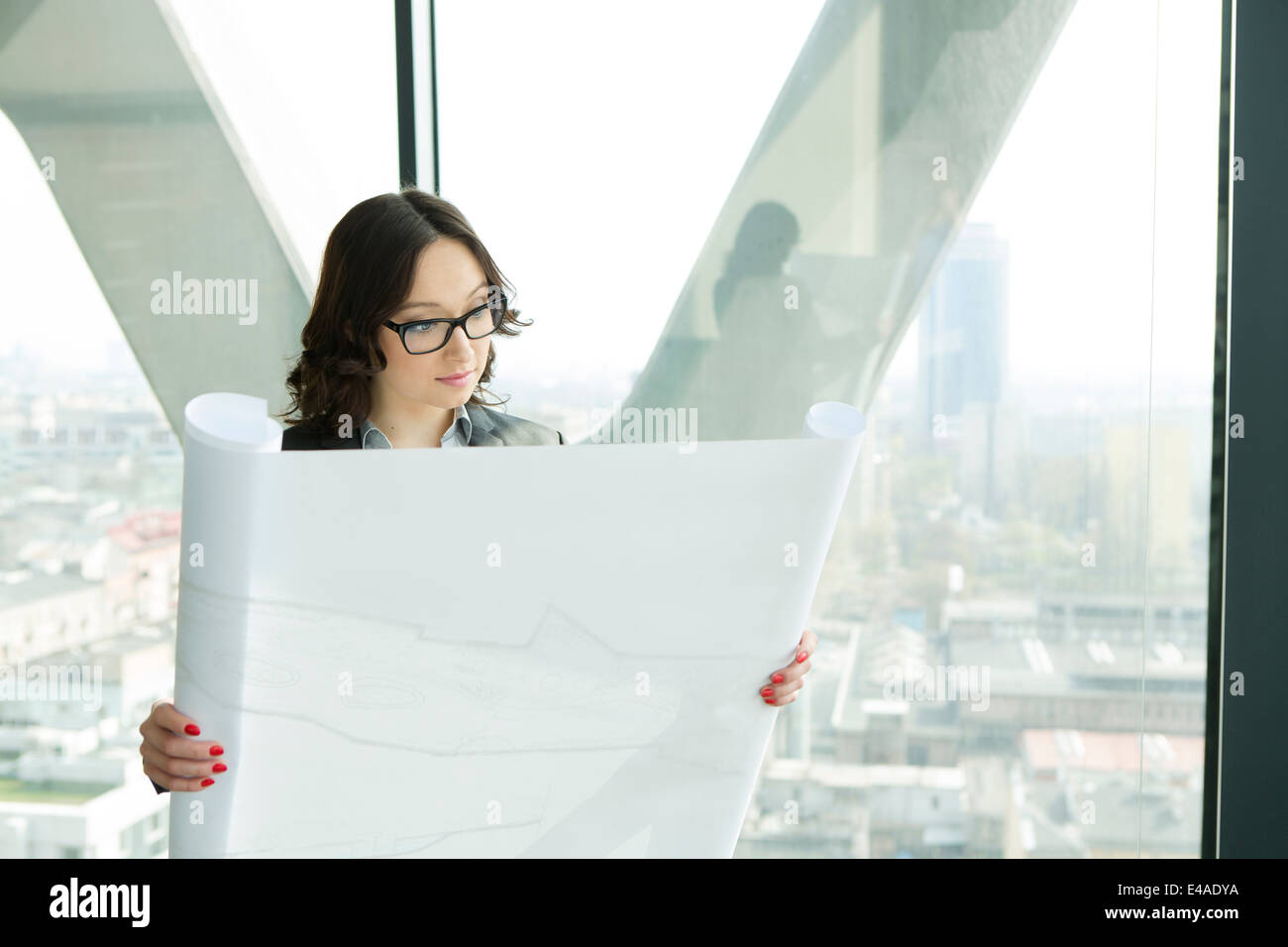 Businesswoman in office looking at blueprint Stock Photo - Alamy