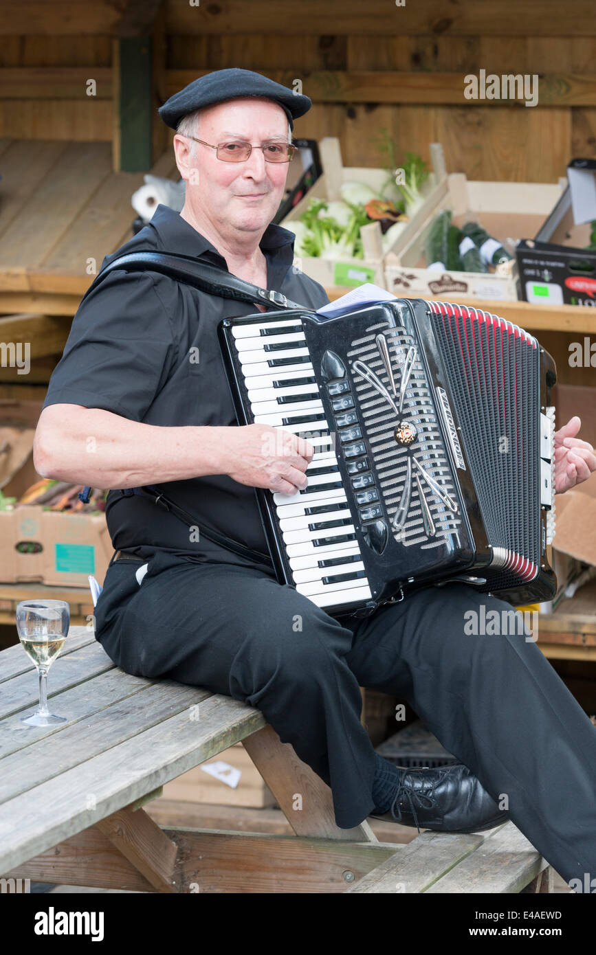 Stapleford near Cambridge, UK. 7th July, 2014.  A musician entertaining crowds at a cafe gets into the Anglo-French spirit at Great Shelford, a village on the route from Cambridge to London. The race attracted thousands of spectators to Cambridge and the route south to Essex and London. Credit:  Julian Eales/Alamy Live News Stock Photo