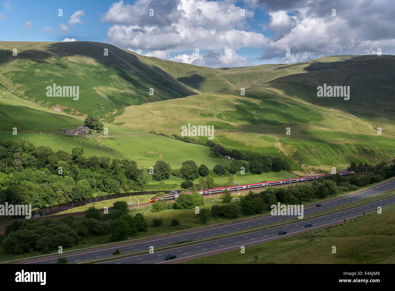 The M6 runs through the Lune Gorge in Cumbria North West England. A Virgin Pendolino heads south on the West Coast Main line. Stock Photo