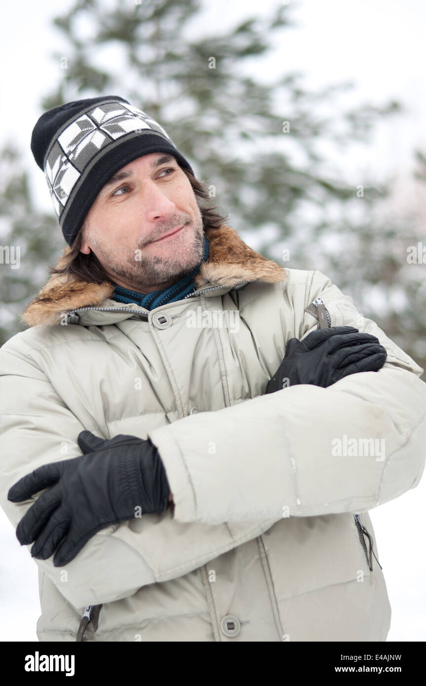 man one phone winter snow talking cell mobile middle age 40 45 jacket hat cap park forest spruce pine fir trees frost frosty com Stock Photo