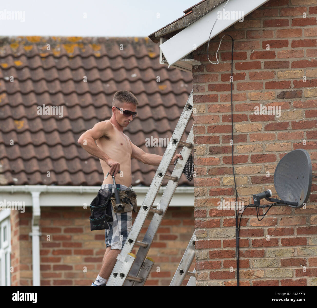 Workman replacing fascia boards on a house roof. Stock Photo