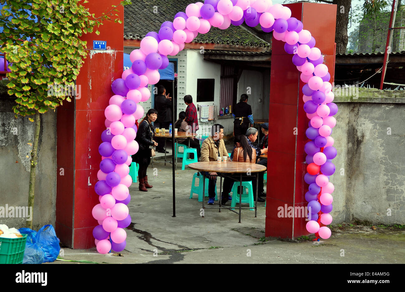 PENGHZOU, CHINA: A garland of pink and purple ballons surrounds a farmhouse doorway at a wedding lunching party Stock Photo