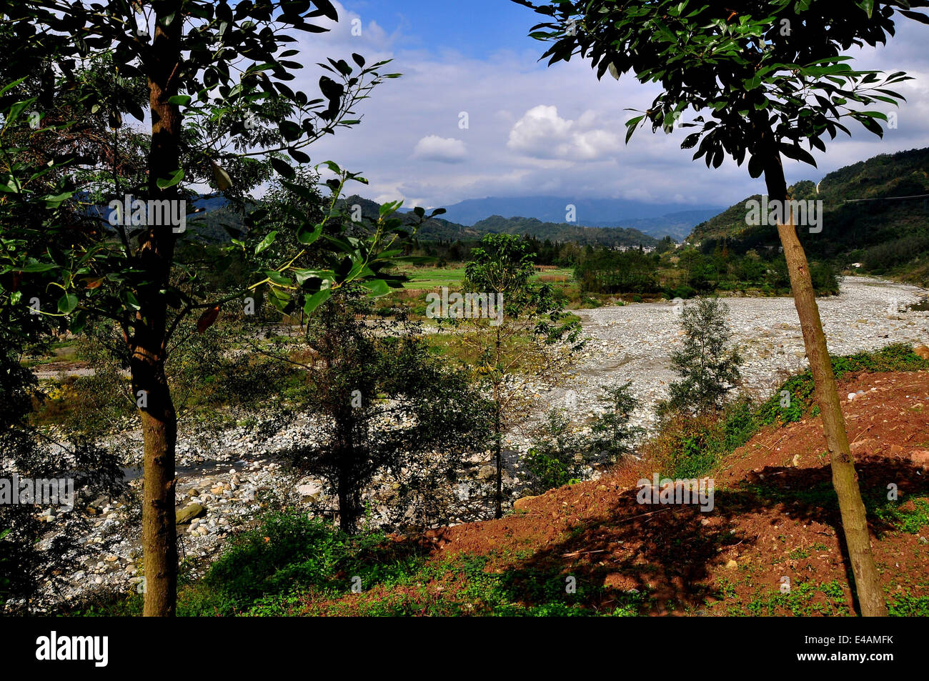 SICHUAN PROVINCE, CHINA: View of the rock-strewn Jianjiang River, farm fields, and distant mountains Stock Photo