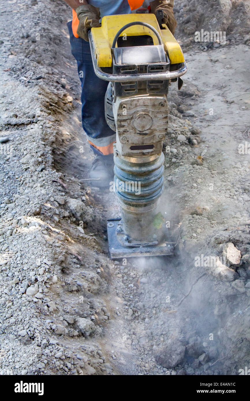 Worker uses compactor to firm soil at worksite Stock Photo Alamy
