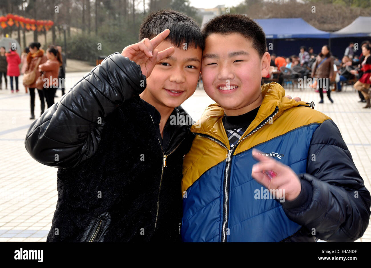 Pengzhou, China: Two young Chinese boys flash the V sign in the plaza at Pengzhou City Park Stock Photo