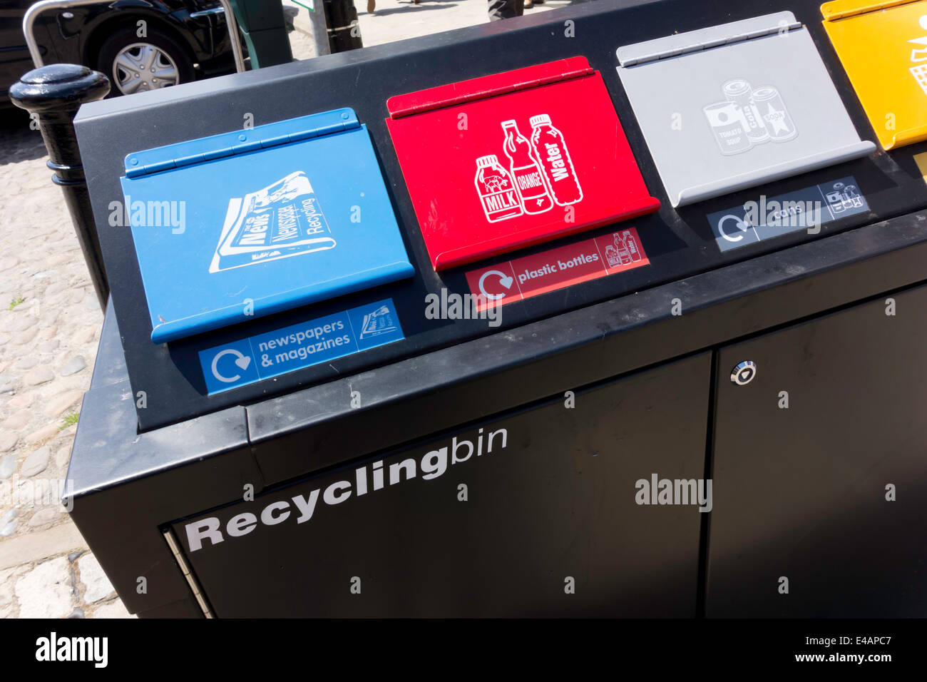 A small recycling bin in a town centre with four compartments for
