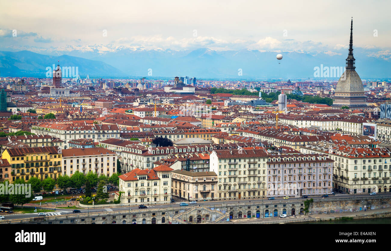 View of the city of Turin, Italy from the Convento Monte dei Cappuccini. On the right the spire of the Mole Antonelliana with a hot air balloon to its left. The Alps rise up in the background. Stock Photo