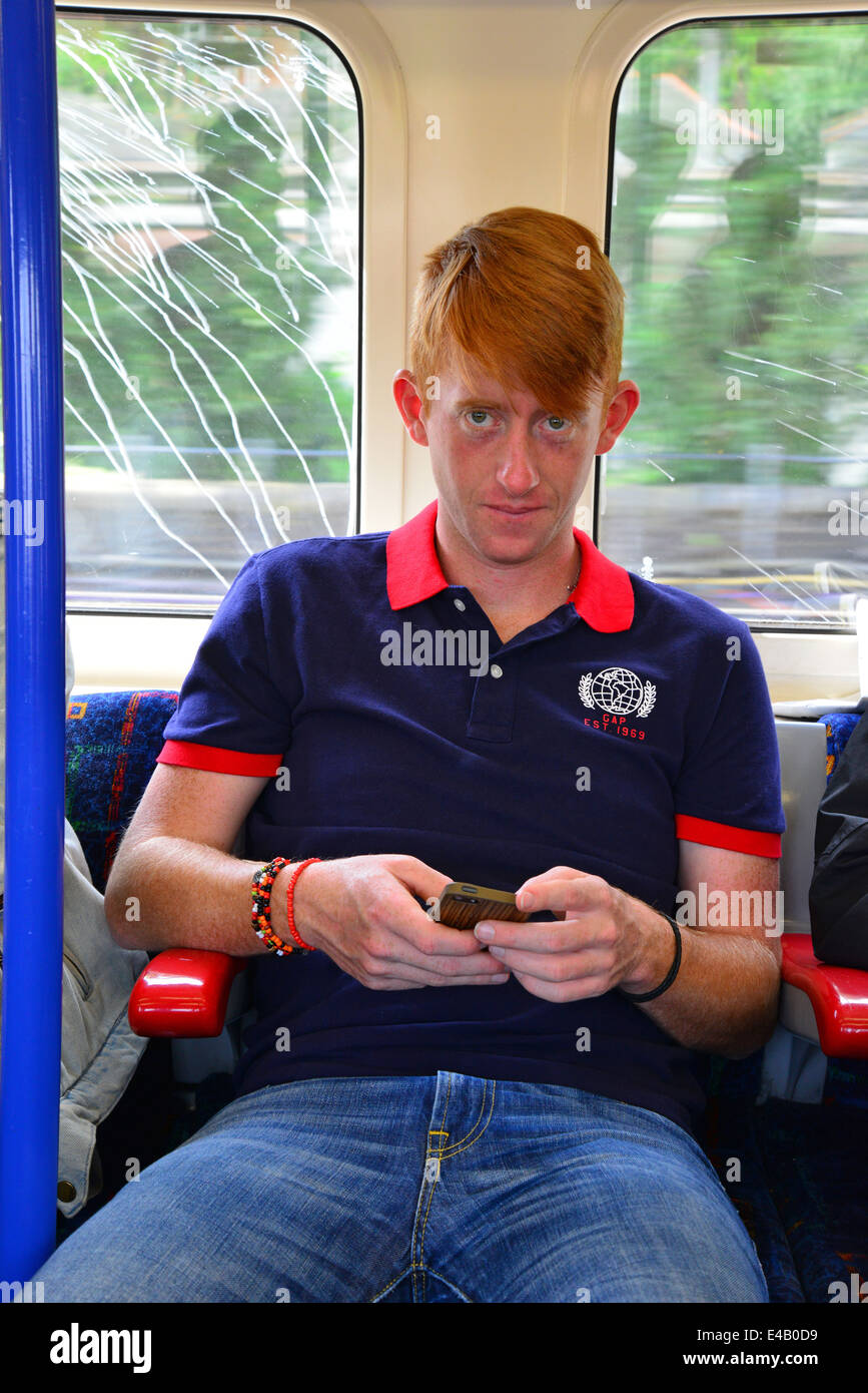 Young man in London Underground train, texting on mobile, Greater London, England, United Kingdom Stock Photo