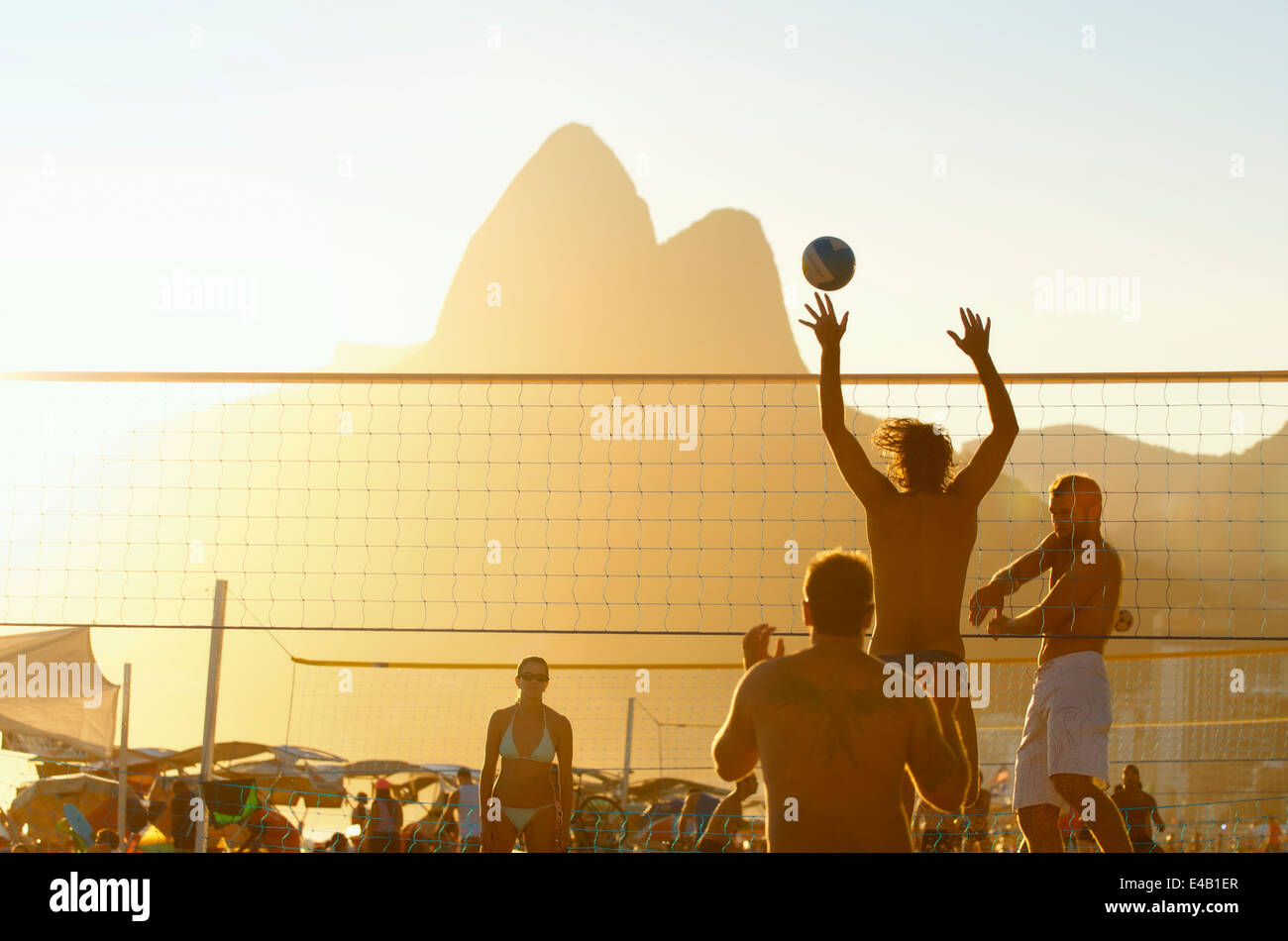 RIO DE JANEIRO, BRAZIL - FEBRUARY 01, 2014: Young carioca Brazilians play a game of beach volleyball against sunset silhouette Stock Photo