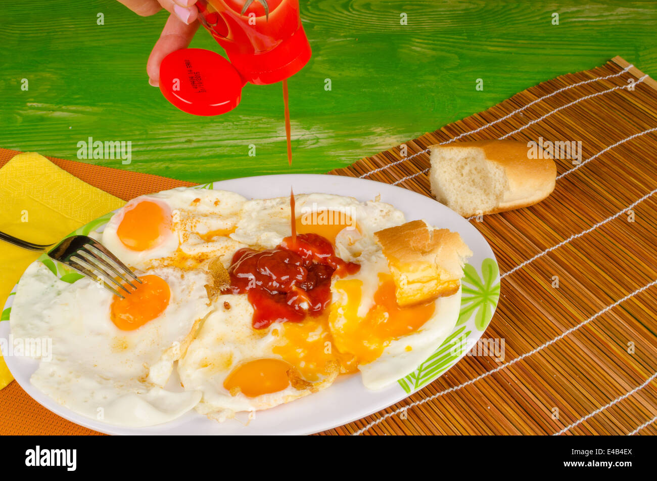 Pouring lots of ketchup on greasy fried egg, an unhealthy nutrition