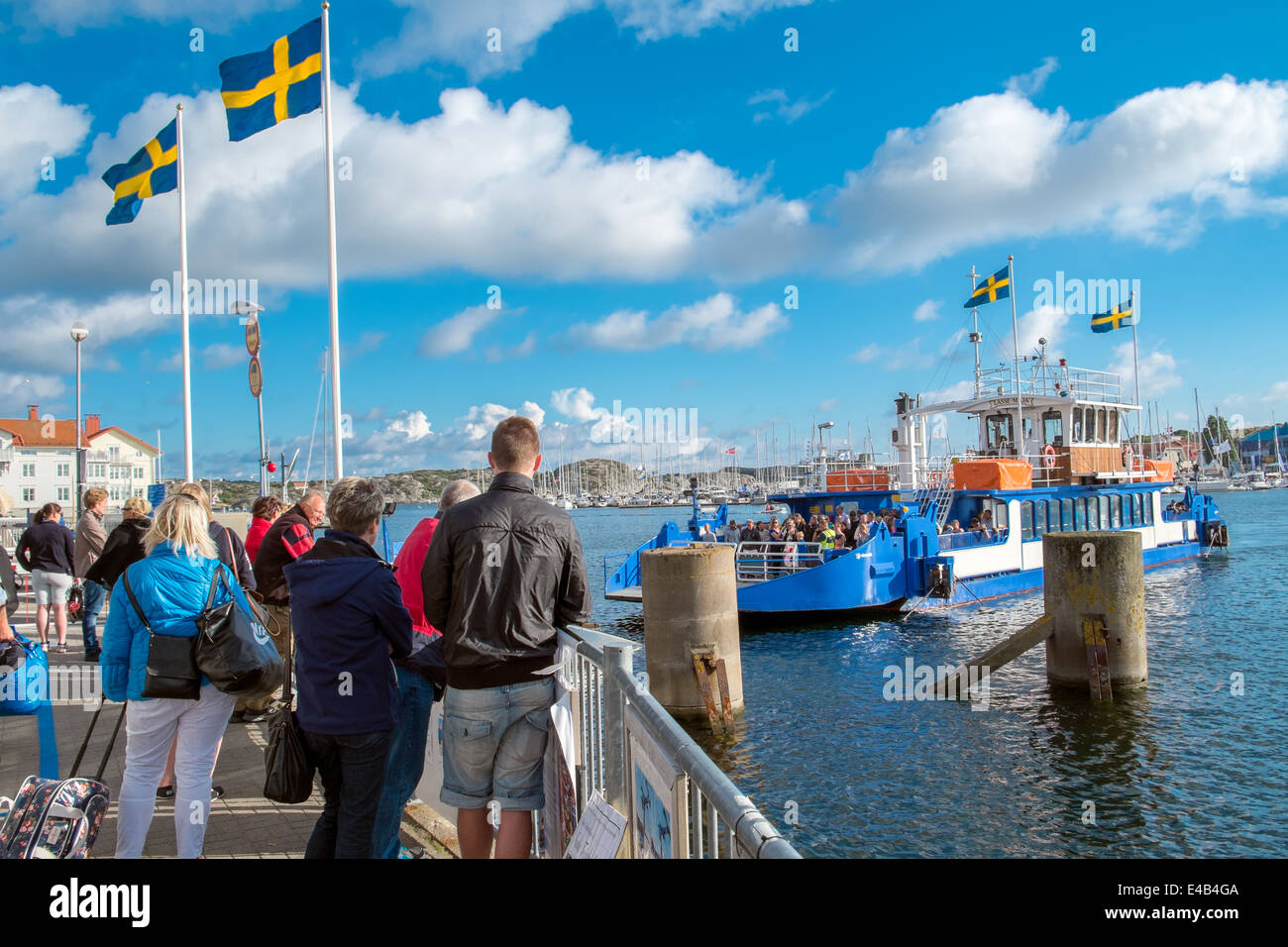 Tourists wait for the ferry that connects the two islands on which Marstrand is located Stock Photo