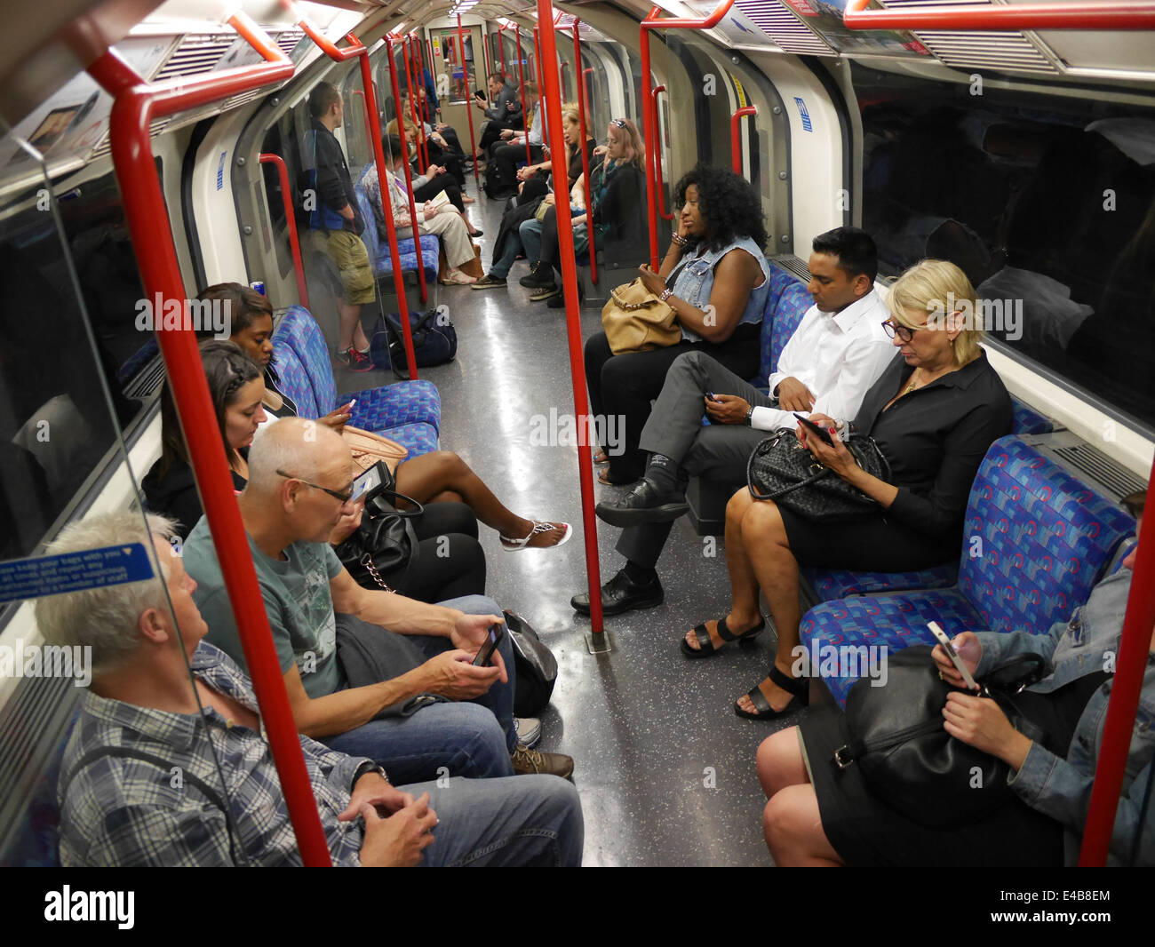 Passengers using mobile phones and tablets on tube train on London
